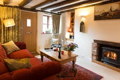 a living room with a red couch and a fireplace at Meddlars a historic cottage on the countryside edge of a vibrant Market Town in Hadleigh