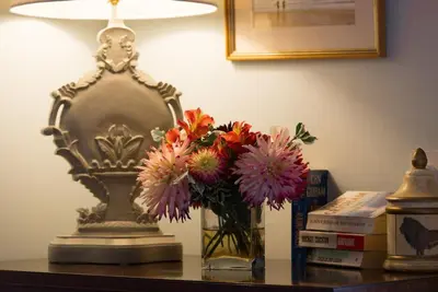 a vase of flowers on a table next to a lamp at The Stables, relax in 5 star style and comfort with lovely walks all around in Great Maplestead