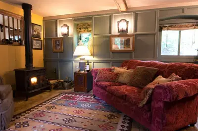 a living room with a red couch and a fireplace at Queenies, an authentic Rural Style coastal cottage in a Nature Reserve in Farnham