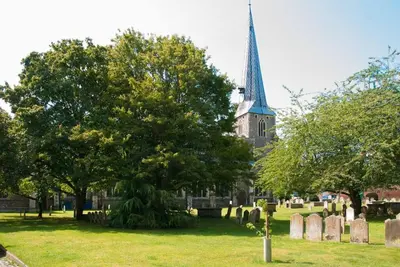 a church with a steeple and a cemetery with trees at The Old Monkey, a quirky bolthole on the edge of a historic Market Town in Hadleigh
