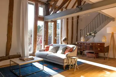 a living room with a white couch and a table at Deepwell Granary is a lovely thatched barn with attached meadow woodland in Buxhall