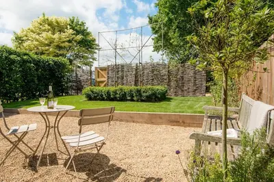 a patio with a table and chairs in a garden at Deepwell Granary is a lovely thatched barn with attached meadow woodland in Buxhall