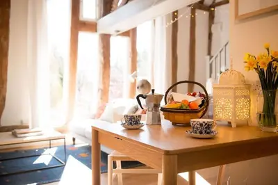 a living room with a table with a bowl of fruit on it at Deepwell Granary is a lovely thatched barn with attached meadow woodland in Buxhall
