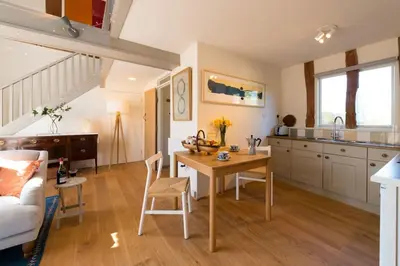 a kitchen and living room with a table and chairs at Deepwell Granary is a lovely thatched barn with attached meadow woodland in Buxhall