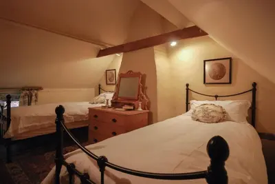 a bedroom with two beds and a mirror on a dresser at Laundry Cottage in a Nature Reserve - Sunday Times 100 coolest Cottages in Farnham
