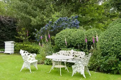 a table and chairs in a garden with flowers at Cissys Cottage in a Nature Reserve, 7 minutes from Aldeburgh seafront in Farnham
