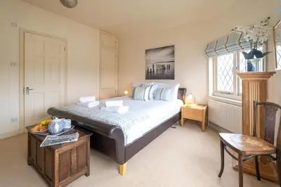 a bedroom with a large bed and a window at The Old Bakery - Aldeburgh Coastal Cottages in Aldeburgh