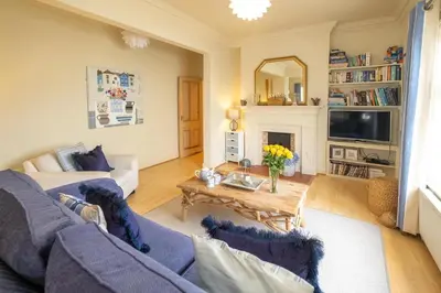 a living room with a blue couch and a table at The Old Bakery - Aldeburgh Coastal Cottages in Aldeburgh