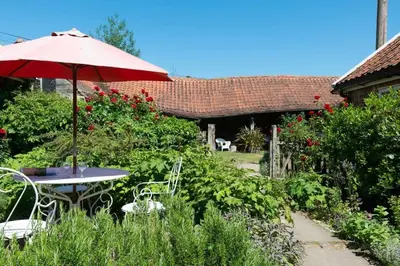 a table and chairs with an umbrella in a garden at Snow Cottage laid back style with footpaths to a great Macro Brewery Pub in Edwardstone