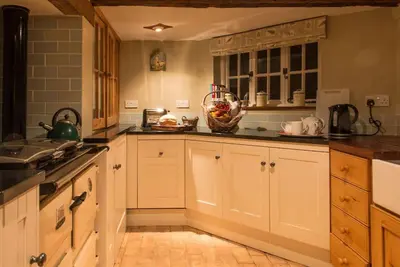 a kitchen with white cabinets and a bowl of fruit at Wren Cottage, a very cosy historic Coastal Cottage in a pretty little village in Wickham Market