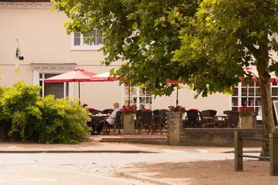 a group of people sitting at a table with umbrellas at Wren Cottage, a very cosy historic Coastal Cottage in a pretty little village in Wickham Market