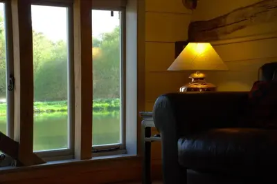 a lamp sitting next to a room with windows at Mill Cottage set beside a Mill pond in a 70 acre Nature Reserve Bliss in Assington