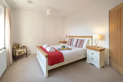 a bedroom with a bed and a chair and a table at Gun Lodge - Aldeburgh Coastal Cottages in Aldeburgh