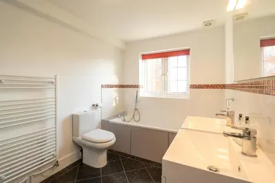 a white bathroom with a toilet and a sink at Gun Lodge - Aldeburgh Coastal Cottages in Aldeburgh