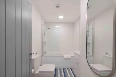 a bathroom with a tub and a sink and a mirror at Town center apartment in Bishops Stortford in Birchanger