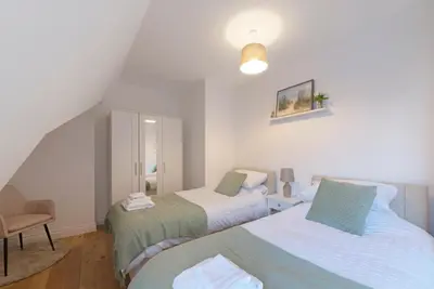 a bedroom with two beds and a chair at Spacious Two Bed loft Apartment in Birchanger