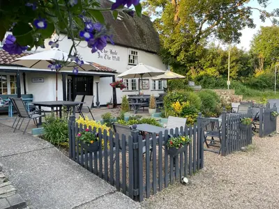 a fence with potted plants in front of a building at The Hole In The Wall in Little Wilbraham