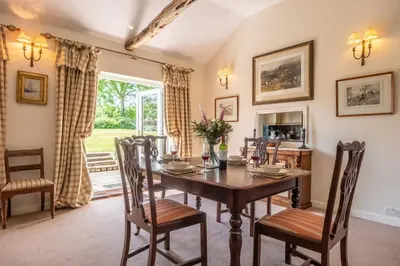 a dining room with a wooden table and chairs at Charming cottage in beautiful countryside with a boating lake - The Calf Pens in Ipswich