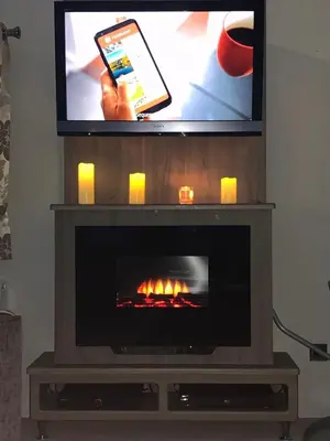 a television with a fireplace with a person holding a cell phone at DaisyChain Getaways The perfect place to Stay Play and Getaway in East Mersea
