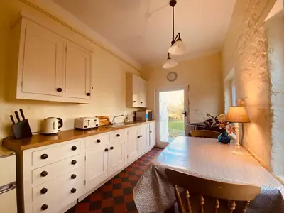 a kitchen with white cabinets and a table in it at Charming Annexe in a rural setting in Newton
