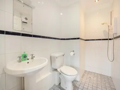 a white bathroom with a toilet and a sink at Peartree Cottage in Saint Osyth