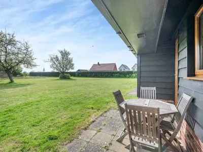 a table and chairs on the porch of a house at Peartree Cottage in Saint Osyth