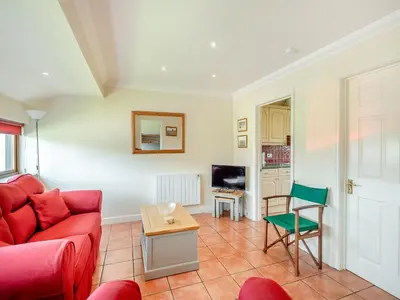 a living room with a red couch and a table at Peartree Cottage in Saint Osyth