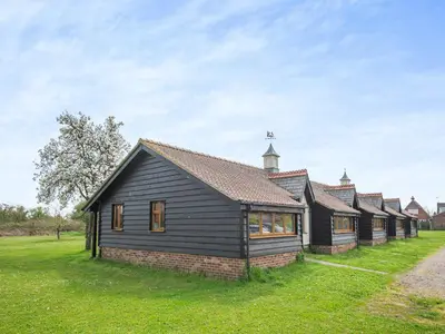 a row of houses in a field with a church at Willowtree Cottage in Saint Osyth