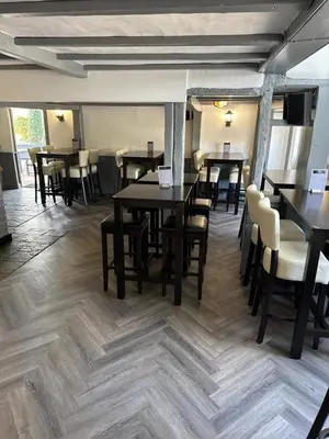 a dining room with tables and chairs in a room with wooden floors at The Fox Inn in Matching