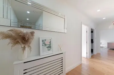 a living room with white walls and a shelf with a plant at Spacious One Bed loft Apartment in Birchanger
