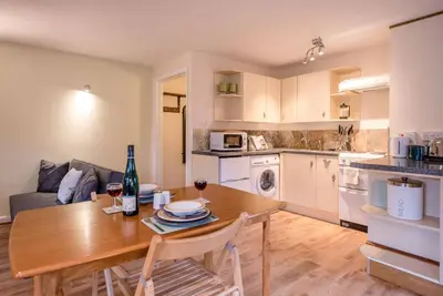 a kitchen and living room with a wooden table and chairs at The Woodshed, Benhall in Saxmundham