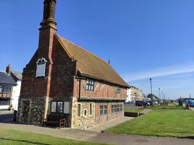 an old brick building with a chimney on a street at Rest Ashored, Aldeburgh in Aldeburgh