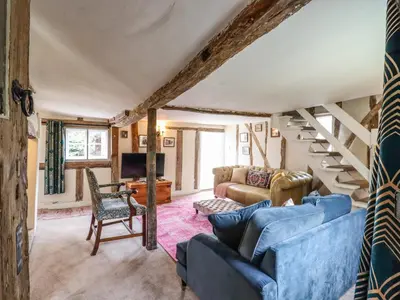 a living room with blue couches and stairs at The Abbey Cottage in Cockfield