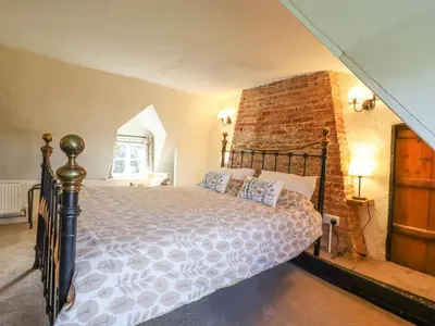 a bedroom with a bed and a brick wall at The Abbey Cottage in Cockfield