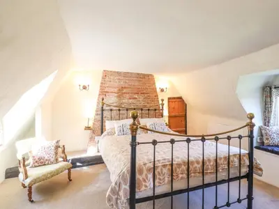 a bedroom with a bed and a chair at The Abbey Cottage in Cockfield