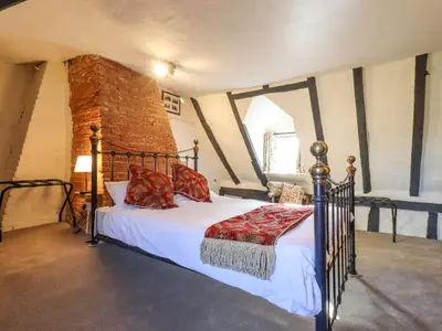 a bedroom with a bed with white sheets and red pillows at The Abbey Cottage in Cockfield