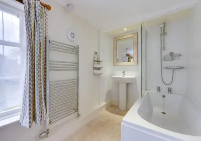 a white bathroom with a tub and a sink at Appletree Cottage in Westleton