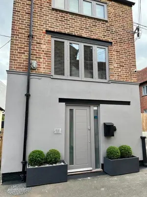 a brick building with a door and two bushes at The Tower, 1 bed 1850's Tiny House in Maldon