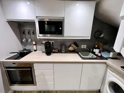 a kitchen with white cabinets and a microwave at The Tower, 1 bed 1850's Tiny House in Maldon