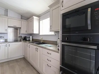 a kitchen with white cabinets and black appliances at Skylarks in Hengrave