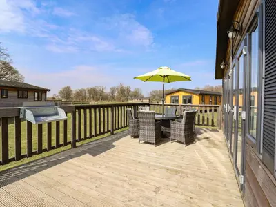 a wooden deck with a table and an umbrella at Skylarks in Hengrave