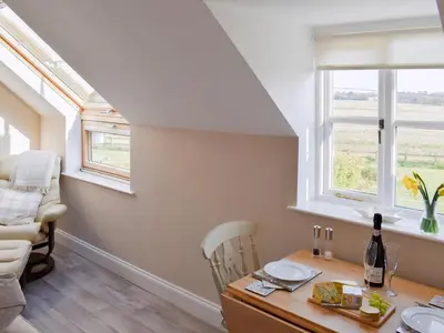 a kitchen with a table and chairs and two windows at The Stables in Bealings