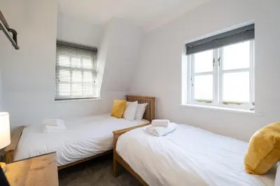 two twin beds in a room with two windows at 15 Mill Field - Aldeburgh Coastal Cottages in Aldeburgh