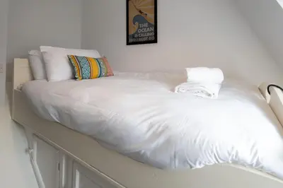 a large bed with white sheets and pillows on it at 15 Mill Field - Aldeburgh Coastal Cottages in Aldeburgh