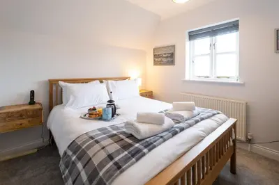 a bedroom with a large bed with towels on it at 15 Mill Field - Aldeburgh Coastal Cottages in Aldeburgh