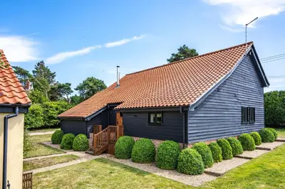 a black house with a red roof at Moles Meadow in Middleton