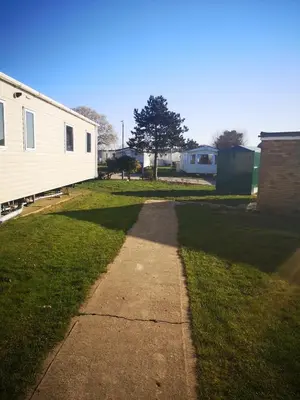 a sidewalk in a field with a building and grass at Lovely 2-Bed caravan in Walton on the Naze in Walton-on-the-Naze