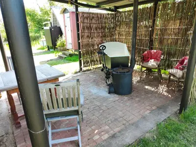 a patio with a grill and a bench and a trash can at Stompy's Hut in Laxfield