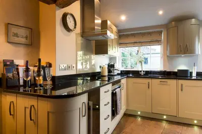 a large kitchen with a counter with a clock on the wall at Miller Cottage a luxury 1550's cottage in the Historic centre of Saffron Walden in Saffron Walden