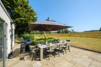 a table with an umbrella on a patio at White Cottage, Iken - Aldeburgh Coastal Cottages in Snape